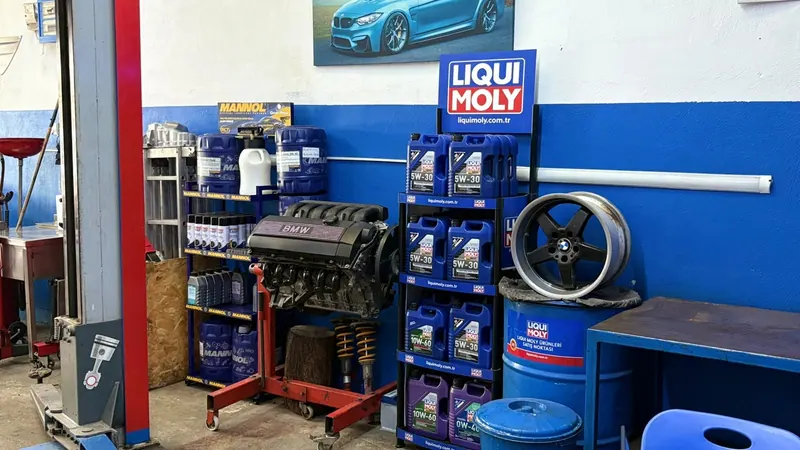 Atölyedeki motor yağı ve bakım ürünleri reyonu, yanında sökülmüş bir BMW motoru